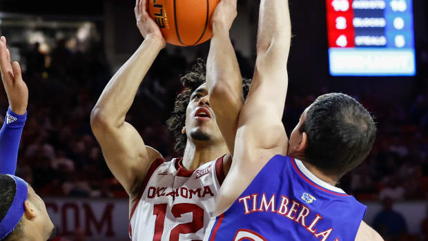 Feb 17, 2024; Norman, Oklahoma, USA; Oklahoma Sooners guard Milos Uzan (12) shoots as Kansas Jayhawks guard Nicolas Timberlake (25) defends during the second half at Lloyd Noble Center. Mandatory Credit: Alonzo Adams-USA TODAY Sports  